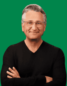 A portrait photo of Mark Ryski, smiling at the camera with arms folded